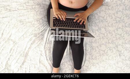 Vue aérienne d'une femme enceinte assise sur le canapé et travaillant sur un ordinateur portable Banque D'Images