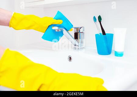 Femme qui fait des tâches dans la salle de bains, nettoyage du robinet d'eau ou du lavabo et du robinet. Concept d'hygiène quotidienne de la salle de bain Banque D'Images