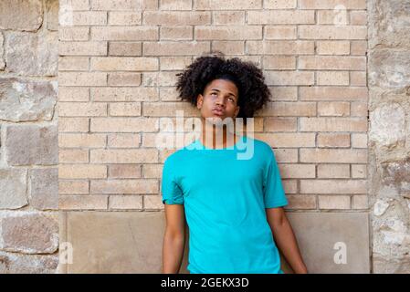 Afro latin homme adolescent contre un mur, regardant vers le haut. Banque D'Images