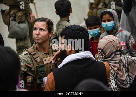 Un Airman des États-Unis avec la Force opérationnelle interarmées - intervention en cas de crise parle avec des familles qui attendent un traitement lors d'une évacuation à l'aéroport international Hamid Karzaï, en Afghanistan, le 20 août. Les membres du service américain aident le ministère d'État à effectuer une opération d'évacuation non combattantes (NEO) en Afghanistan. (É.-U. Photo du corps marin par Cpl. Davis Harris) Banque D'Images