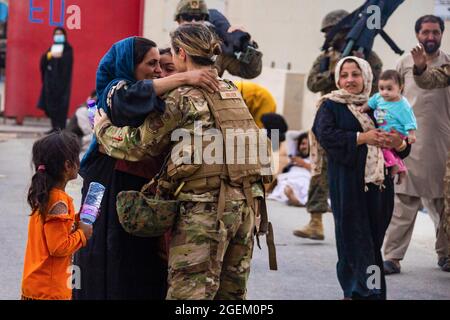 Un Airman des États-Unis avec la Force opérationnelle conjointe - réponse de crise embrasse mère après avoir aidé à réunir leur famille à l'aéroport international Hamid Karzaï, Afghanistan, août 20. Les membres du service américain aident le ministère d'État à effectuer une opération d'évacuation non combattantes (NEO) en Afghanistan. (É.-U. Photo du corps marin par Cpl. Davis Harris) Banque D'Images