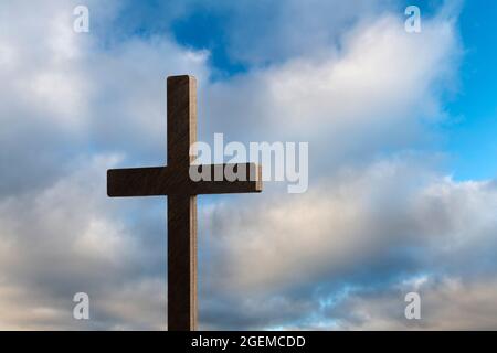 Image dramatique montrant une croix d'église religieuse encadrée d'un ciel bleu et nuageux. Espace de copie disponible à droite de la croix. Banque D'Images