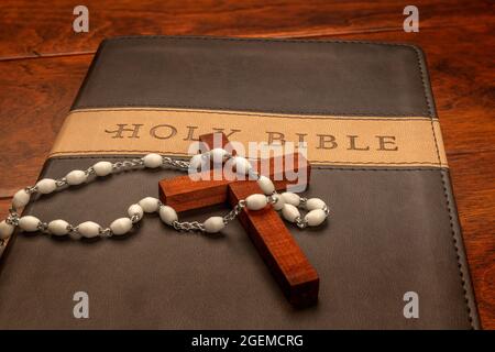 La croix religieuse d'un prêtre drapée de perles Crucifix repose sur une bible avant leur sermon. Banque D'Images