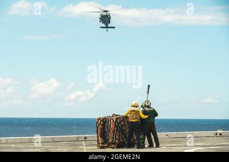 OCÉAN PACIFIQUE (août 14, 2021) les Marines des États-Unis avec la 11e unité expéditionnaire maritime (UMM) et un marin affecté au quai de transport amphibie USS Portland (LPD 27), se préparent à transporter des cargaisons sous un HMH-60S Sea Hawk affecté à l'Escadron de combat en mer des hélicoptères 4 au cours d'une reconstitution verticale en mer, le 14 août. Les Marines et les marins du 11e MEU et du groupe de prêt amphibie d'Essex (ARG) sont en cours d'exécution des opérations de routine dans la 3e flotte américaine. (É.-U. Photo du corps marin par Sgt. Alexis Flores) Banque D'Images