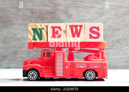 Jouet feu échelle camion tenir le bloc de lettres dans les nouvelles de mot sur fond de bois Banque D'Images