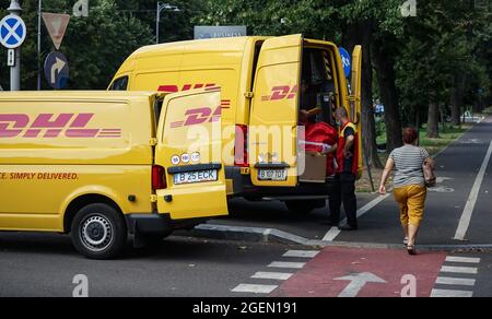 Bucarest, Roumanie - 20 août 2021 : deux fourgonnettes de livraison jaunes DHL sont vues transférer des colis dans une rue de Bucarest. Cette image est destinée à l'editoria Banque D'Images