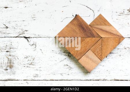 Puzzle Tangram en forme de coeur sur fond de bois blanc ancien Banque D'Images