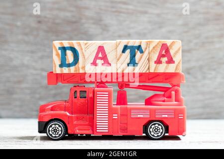 Le camion d'échelle de feu de jouet tient le bloc de lettres dans les données de mot sur fond de bois Banque D'Images