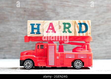 Jouet échelle incendie camion tenir bloc de lettres dans le mot dur sur fond de bois Banque D'Images