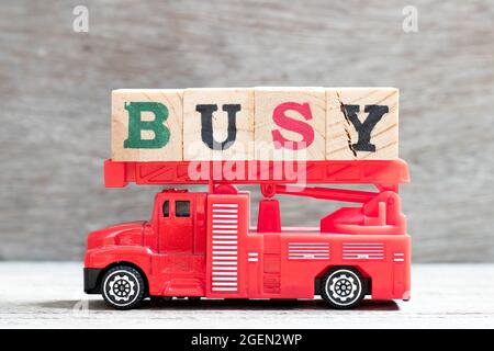 Jouet échelle incendie camion tenir le bloc de lettres dans le mot occupé sur fond de bois Banque D'Images