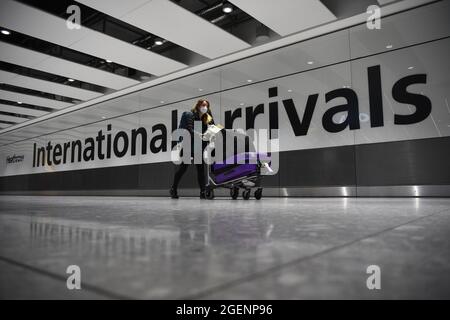 Photo du dossier datée du 18/01/21, d'un passager qui pousse des bagages dans le hall des arrivées du terminal 5 de l'aéroport Heathrow de Londres. Les vacanciers ont été soumis à 50 changements dans les règles pour les voyages internationaux depuis le premier confinement du coronavirus, selon une nouvelle analyse de PA Media. Un nombre similaire de changements s'est produit en Écosse, au pays de Galles et en Irlande du Nord, les administrations dévotées ayant largement reflété les règles de l'Angleterre. Date de publication : samedi 21 août 2021. Banque D'Images