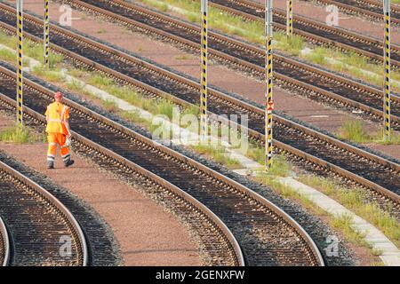 Halle, Allemagne. 21 août 2021. Un employé de chemin de fer traverse les voies de l'installation de formation des trains pour les trains de marchandises à la station de fret de Halle. Le syndicat allemand des conducteurs de train (GDL) a demandé à ses membres de faire grève samedi à mercredi à la Deutsche Bahn AG (DB). Au départ, le trafic de marchandises doit faire grève samedi, suivi du trafic de passagers à partir de lundi. Credit: Peter Endig/dpa-Zentralbild/dpa/Alay Live News Banque D'Images