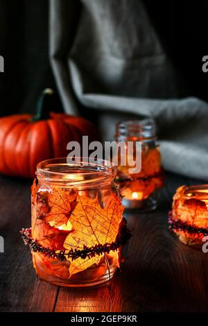 Lanterne d'automne faite d'un pot en verre décoré de feuilles colorées et d'une couronne de bruyère. Bougie à l'intérieur. Banque D'Images