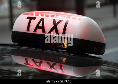 Panneau de toit éclairé avec le mot TAXI attaché à un véhicule dans une rue de Paris, France Banque D'Images