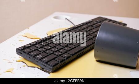 Gros plan d'un clavier imprégné de café avec une tasse retournée à proximité Banque D'Images