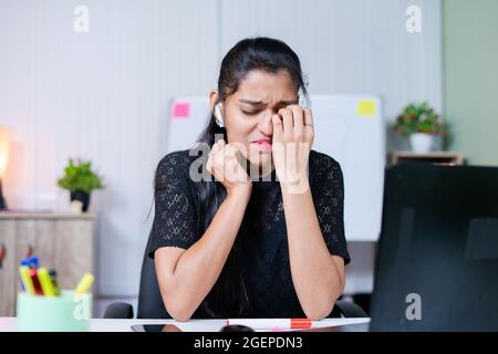 prise de vue moyenne d'une jeune femme indienne frustrée et triste qui pleure sur le lieu de travail - concept de stress émotionnel, mental ou professionnel au bureau. Banque D'Images