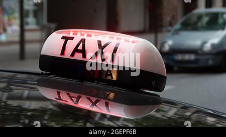 Panneau de toit éclairé avec le mot TAXI attaché à un véhicule dans une rue de Paris, France Banque D'Images