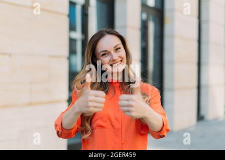 Une femme de trente ans sourit et montre ses mains avec ses pouces Banque D'Images
