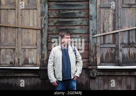 Un fermier campagnard se tient près d'un bâtiment en bois abandonné vide. Banque D'Images