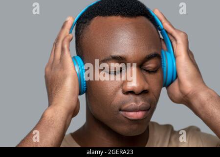 Jeune homme à la peau sombre dans un casque qui écoute de la musique Banque D'Images