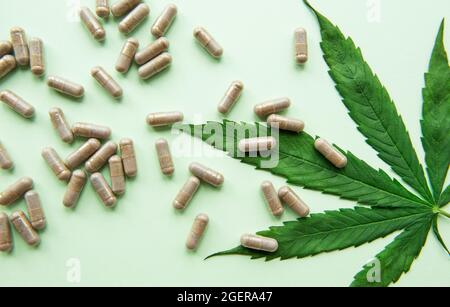 Pilules de CBD. Groupe de capsules claires de cannabis CBD et de feuille de chanvre sur fond vert Banque D'Images