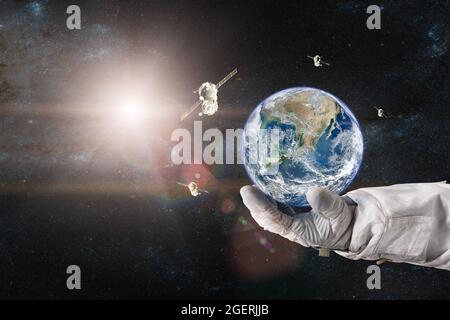 La terre avec un vaisseau spatial lancé dans l'espace entre les mains de l'astronaute. Éléments de cette image fournis par la NASA. Banque D'Images