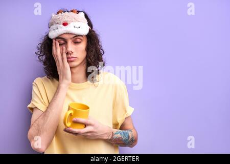Fatigué détendu Homme ne veut pas aller étudier ou travailler, debout avec Mug dans les mains avec les yeux fermés, veulent dormir. Arrière-plan violet isolé Banque D'Images