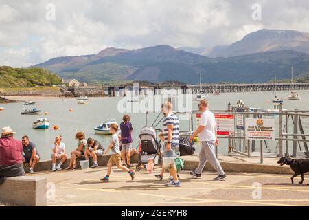 Holiday Makers près du port sur la rivière Mawddach estuaire à marée basse à la station balnéaire de Barmouth Gwitt Banque D'Images