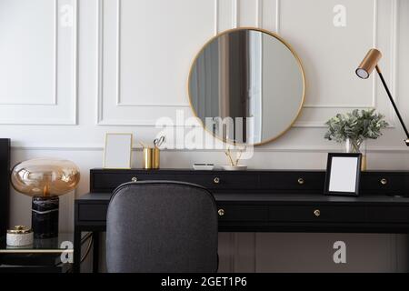 Intérieur moderne de table de maquillage scandinave avec noir et blanc, commode design, vase à feuilles, coussin confortable et accessoires élégants. Modèle. Élégant Banque D'Images