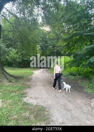 Une femme marche son chien le long d'un patrh près du lac à Prospect Park, Brooklyn, New York. Banque D'Images