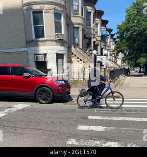 Un juif orthodoxe plus âgé passe son vélo dans le quartier de Borough Park à Brooklyn, New York. Banque D'Images