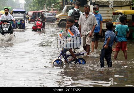 New Delhi, Inde. 21 août 2021. Un enfant fait un vélo dans une rue où l'eau est engorée après de fortes pluies dans la région de Jahangirpuri à New Delhi. En raison des fortes précipitations qui ont conduit à l'exploitation forestière de l'eau dans de nombreuses régions, la police de la circulation de Delhi a fermé plusieurs passages inférieurs et routes pour éviter les embouteillages pour les navetteurs. Le Service météorologique indien (IMD) a annoncé que les orages et les pluies se poursuivent dans la capitale nationale. Crédit : SOPA Images Limited/Alamy Live News Banque D'Images