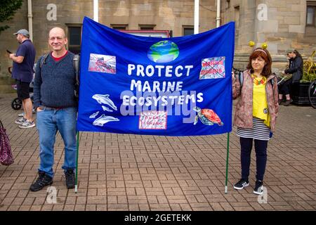 Alloa, Écosse, Royaume-Uni. 21 août 2021. Deux spectateurs tiennent une bannière. STORM, par compagnie de théâtre, Vision Mechanics, promenades à Alloa. Cette marionnette de 10 mètres de haut raconte l'histoire des océans en crise. STORM est une déesse mythique de la mer, entièrement faite de matériaux recyclés et naturels. Le projet nous encourage tous à célébrer nos mers, à prendre soin de nos côtes et à donner la priorité à l'environnement. Credit: Iain McGuinness / Alamy Live News Banque D'Images