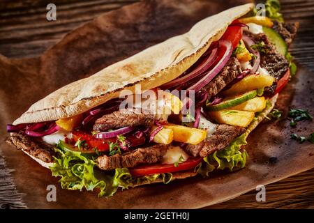 Faire don de kebab dans du pain pita avec du poulet et des légumes placés sur une table en bois Banque D'Images