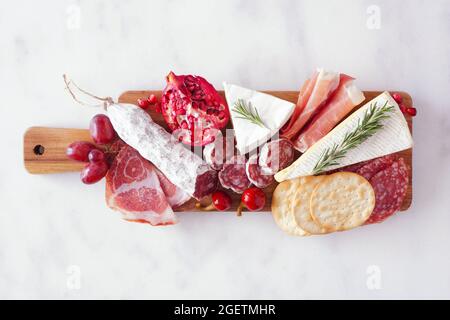 Plateau de service composé de viandes, fromages et hors-d'œuvre variés. Vue de dessus sur un fond en marbre blanc. Banque D'Images