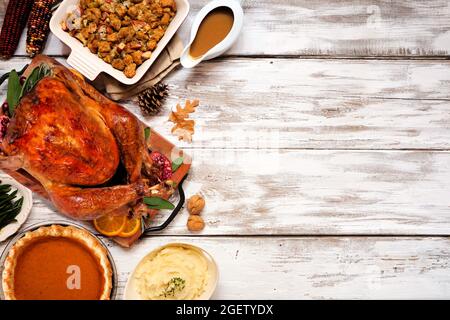 Dîner traditionnel de Thanksgiving avec dinde. Vue de dessus, bordure latérale sur un arrière-plan rustique en bois blanc avec espace de copie. Dinde, farce, purée de pommes de terre et Banque D'Images