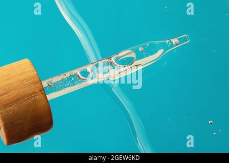 Pipette de compte-gouttes avec couvercle en bois sur le gel de gelée.vue du dessus, cosmétique liquide.bannière bleue avec espace de copie. Banque D'Images