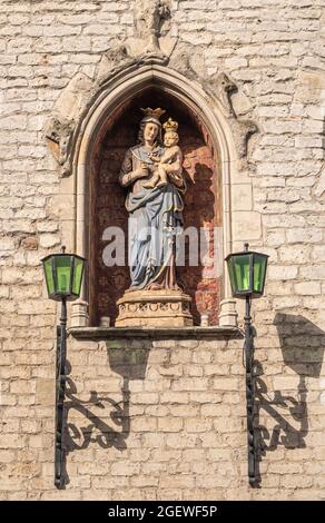 Gand, Flandre, Belgique - 30 juillet 2021 : gros plan de la statue en pierre colorée de madonna avec l'enfant installé dans la niche de la façade en brique beige de Vleeshuis, le moi Banque D'Images