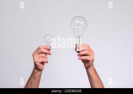 deux ampoules dans les mains des hommes. grandes et petites lampes à incandescence. Banque D'Images