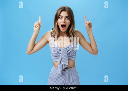 Une femme qui s'étonne de la mâchoire de l'étonnement souriant de manière générale regarder à l'appareil-photo étonnait de lever les mains et de pointer vers l'impressionnant copier l'espace Banque D'Images