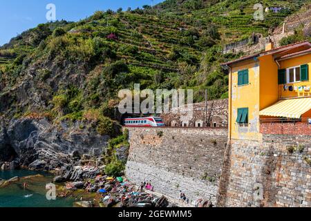 Vernazza, Italie - 10 août 2021 : le train de voyageurs entre dans le tunnel ferroviaire près du village de Vernazza Banque D'Images