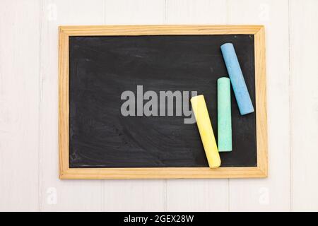 Morceaux de craie sur un tableau noir d'école sur fond blanc en bois. Vue de dessus. Copier l'espace Banque D'Images