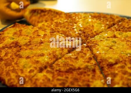 détail d'une grande pizza familiale avec quatre fromages tels que le parmesan de mozzarella gorgonzola et la ricotta coupés en portions pour la restauration rapide partagée avec des amis Banque D'Images