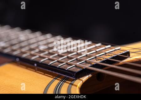 Partie d'une guitare acoustique, fretboard de guitare avec cordes sur fond noir. Banque D'Images