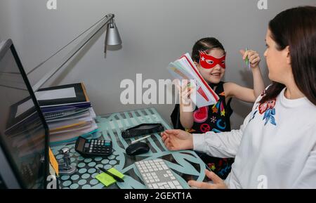 Femme travaillant de la maison avec sa fille l'interrompant Banque D'Images