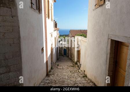 Vue sur la rue du village Vuno - maisons blanches traditionnelles avec toits d'orange et volets en bois sur les fenêtres, sur la colline de montagne, au sud de l'Albanie Banque D'Images