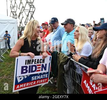 Cullman, Alabama, États-Unis. 21 août 2021. L'ancien président Donald Trump organise un rassemblement dans le nord de l'Alabama, s'adressant à des milliers de partisans dans un champ baigné de pluie et de boue.en photo : la députée de Géorgie Marjorie Taylor Green détient un signe d'impeachment Biden alors qu'elle accueille la foule et pose pour des photos. (Image de crédit : © Robin Rayne/ZUMA Press Wire) Banque D'Images