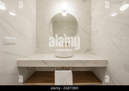 vue avant de l'évier et du comptoir en marbre blanc avec nervures grises et robinets dorés Banque D'Images