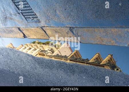 Réflexions de bâtiments dans une flaque le long d'un des grands boulevards parisiens Banque D'Images