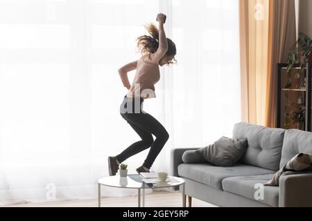 Fou bonne jeune femme tenant le téléphone portable saute seule à l'intérieur Banque D'Images